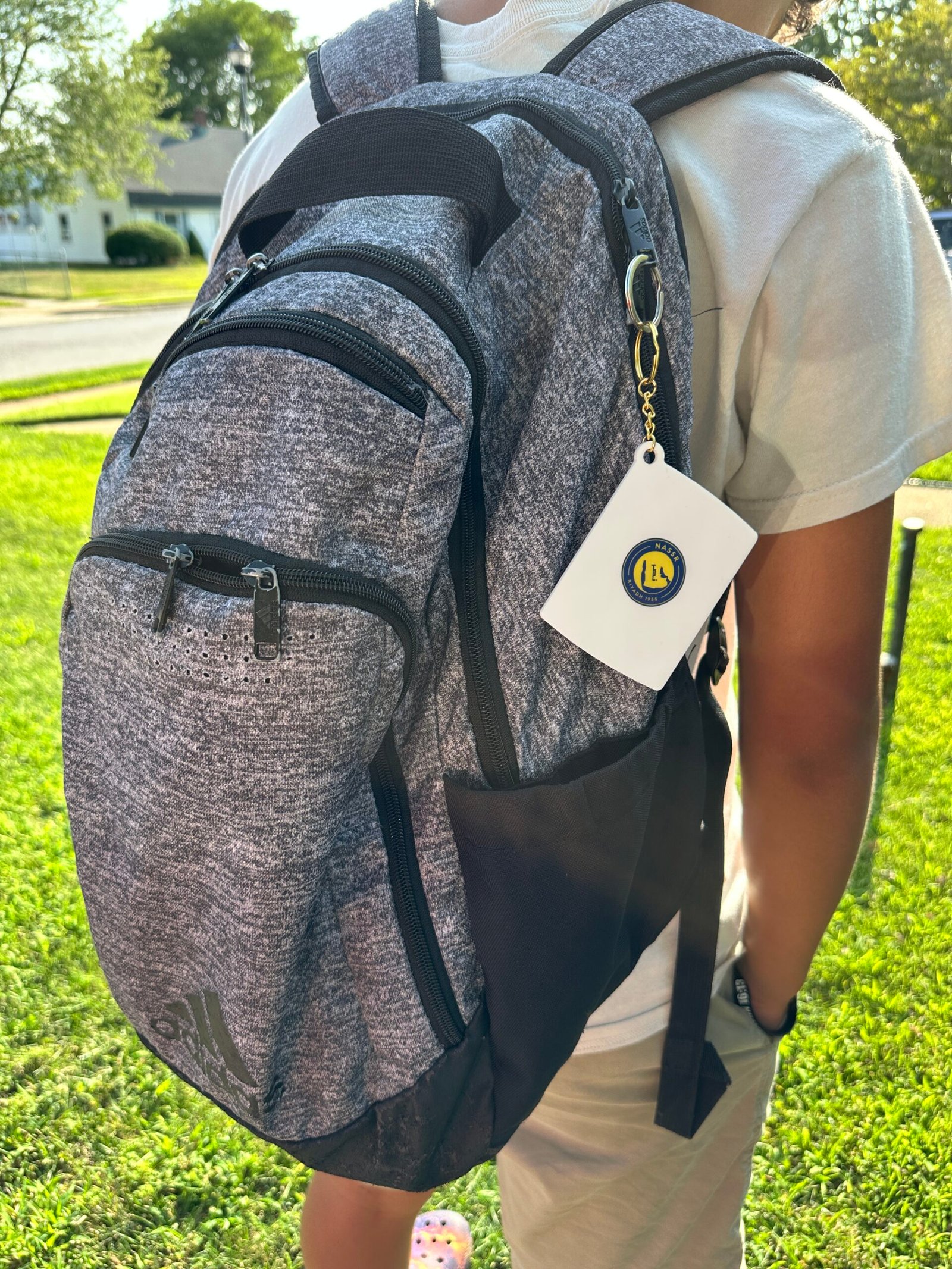 Custom keychain with logo attached to Adidas gray backpack personalized accessory for students and sports fans